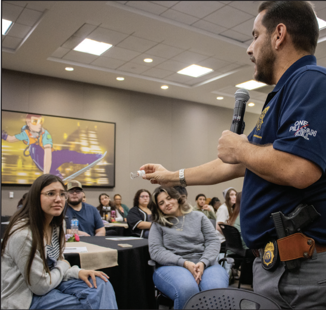 DEA special agent Eduardo Chavez shows NE student Natalia Rich and SE student Alexa Gonzalez how small a dosage of fentanyl can kill someone.